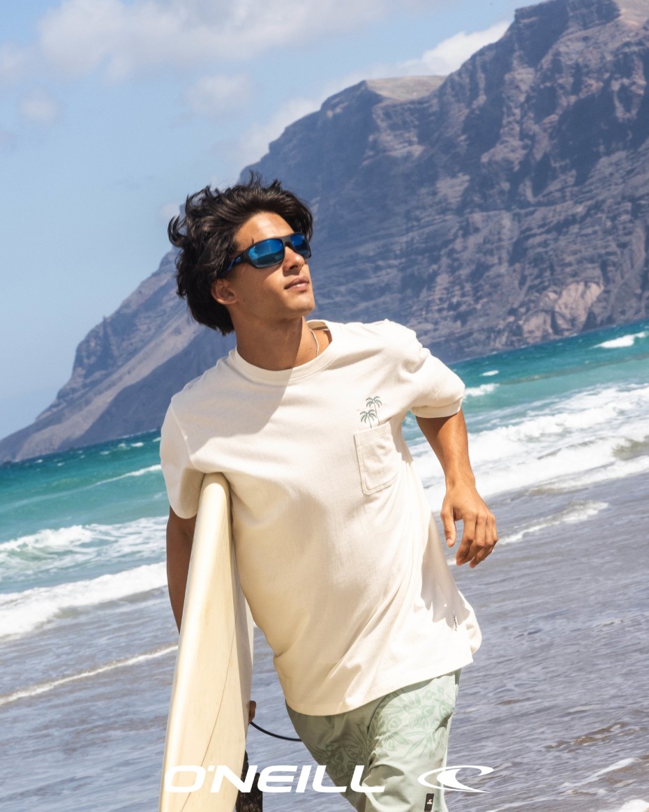 ONeill: Mann mit Sonnenbrille und Surfbrett joggt am Strand