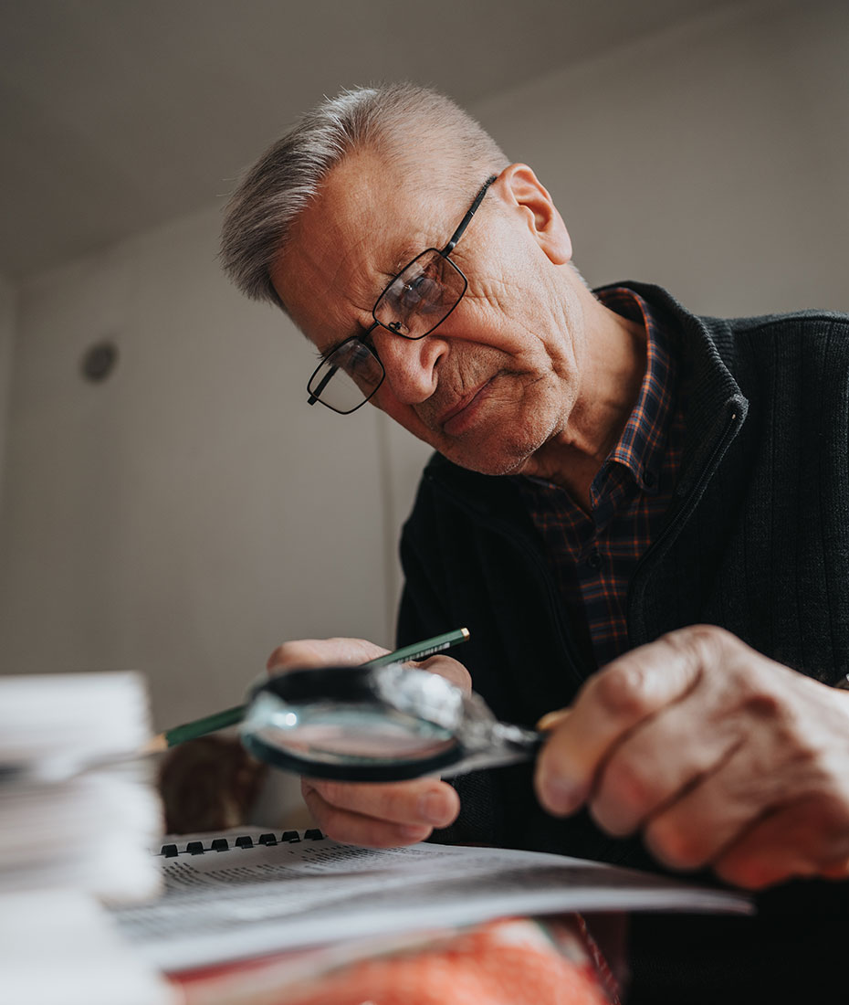 Älterer Mann mit Brille hat kleines Kind auf dem Schoss sitzen. 